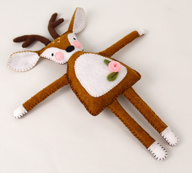 Plush red deer handmade from felt, with a pink flower, pink cheeks, and stitched embellishments