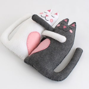 Felt hand stitched hugging cats lying on back