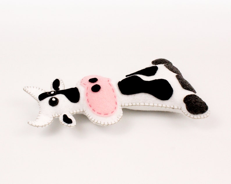 Black and white cow stuffie, hand sewn, lying on back