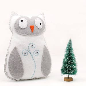 Sewing pattern for a hand stitched felt owl, pictured next to a bottle brush tree