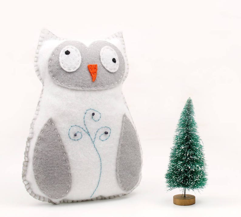 Sewing pattern for a hand stitched felt owl, pictured next to a bottle brush tree