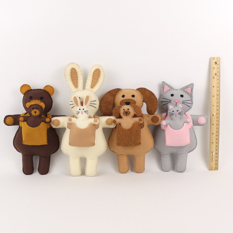 Felt bear, rabbit, dog, and cat along with infants in carriers next to a ruler