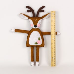 A plush felt deer, hand-stitched, next to a ruler