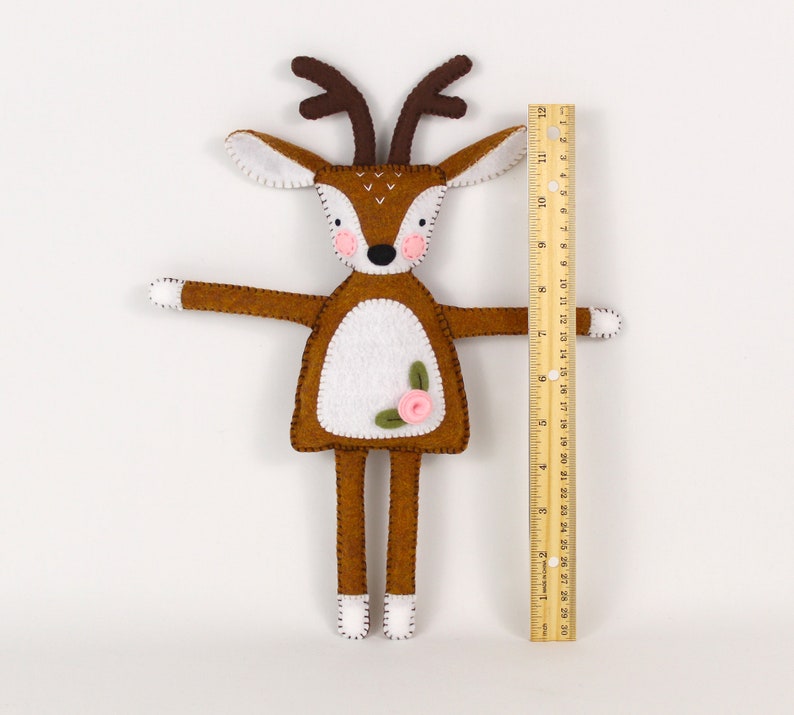 A plush felt deer, hand-stitched, next to a ruler