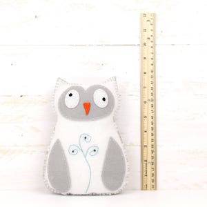 Felt hand sewn owl next to a ruler to show relative size
