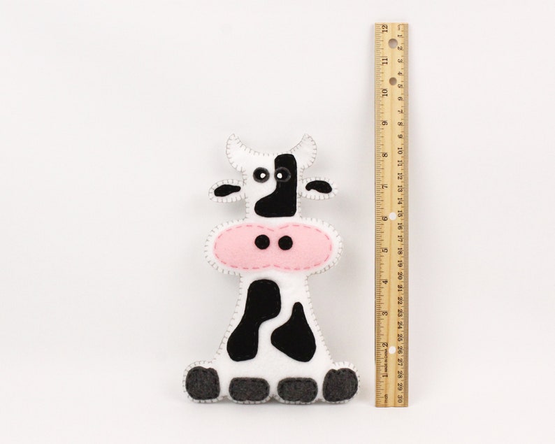 Felt cow stuffed animal next to a ruler