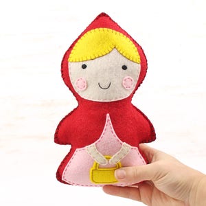 Hand holding a hand stitched felt little red riding hood