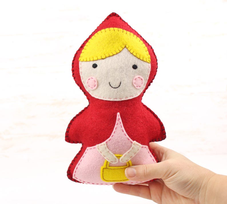 Hand holding a hand stitched felt little red riding hood