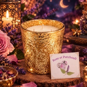 Pode incluir: Uma vela de três pavios num recipiente de vidro de mercúrio dourado. Um rótulo quadrado branco apresenta o texto Rose et Patchouli em fonte roxa, acompanhado por uma ilustração de uma rosa cor-de-rosa e folhas verdes. A vela repousa sobre madeira.