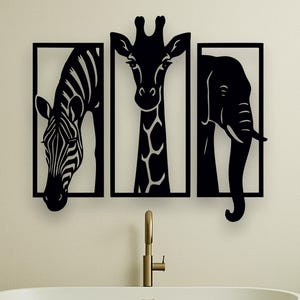 May include: Black metal wall art featuring a zebra, giraffe, and elephant, each within a rectangular frame. The artwork is mounted above a white bathtub in a bathroom setting. The zebra has black and white stripes, the giraffe has a long neck, and the elephant has a curved trunk.