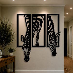 Op de afbeelding: Een driedelige wandkunstset van zwart metaal met een gestileerd zebramotief. Het kunstwerk bestaat uit drie rechthoekige kaders, waarbij de kop en nek van de zebra naar beneden uit de kaders steken, wat zorgt voor een gedurfde, contrastrijke look.