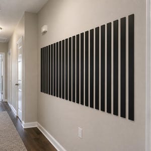 May include: A wall-mounted decorative art piece consisting of a series of vertical black rectangular slats arranged in a row. The slats are uniform in height and width, creating a rhythmic pattern against the light-colored interior wall surface.