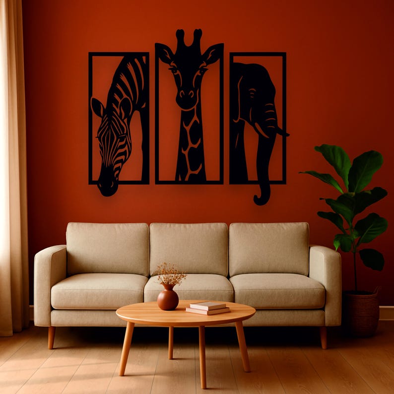 May include: Black metal wall art featuring a zebra, giraffe, and elephant, each within a rectangular frame. The artwork is displayed on a reddish-brown wall above a beige sofa and a wooden coffee table.