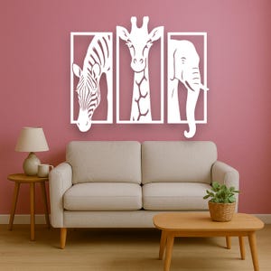 May include: White animal silhouette wall art featuring a zebra, giraffe, and elephant, each within a rectangular frame. The artwork is mounted on a pink wall above a beige sofa and wooden coffee table, creating a modern, minimalist aesthetic.