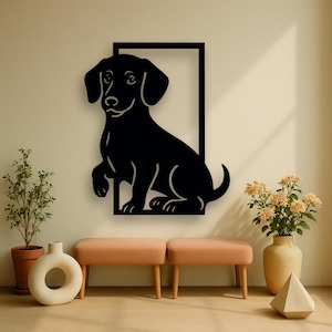 Könnte beinhalten: Schwarze Metall-Wandkunst eines sitzenden Dackelhundes in einem schwarzen rechteckigen Rahmen. Der Hund ist in einem minimalistischen Stil mit klaren Linien dargestellt. Das Kunstwerk ist an einer beigefarbenen Wand angebracht, darunter zwei kleine pfirsichfarbene Bänke.