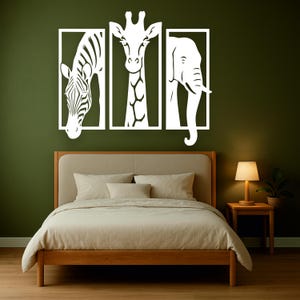May include: White animal silhouette wall art featuring a zebra, giraffe, and elephant, each within a rectangular frame. The artwork is mounted on a dark green wall above a wooden bed frame with beige bedding. A small wooden side table with a lamp is next to the bed.
