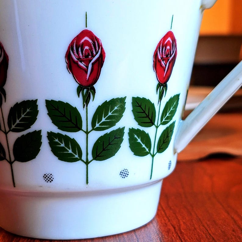 Pu&ograve; includere: Tazza in ceramica bianca con un motivo floreale a rose. La tazza presenta rose rosse con foglie e steli verdi. Il manico &egrave; bianco e la tazza ha una base leggermente svasata.