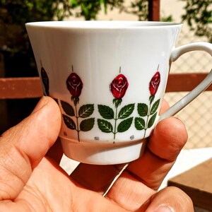 Pu&ograve; includere: Una tazza di ceramica bianca con manico nero e la scritta "But First, Coffee" in grassetto nero. La tazza &egrave; posta su uno sfondo sfocato, che suggerisce un'atmosfera accogliente.