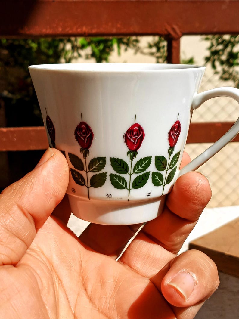 Pu&ograve; includere: Una tazza di ceramica bianca con manico nero e la scritta "But First, Coffee" in grassetto nero. La tazza &egrave; posta su uno sfondo sfocato, che suggerisce un'atmosfera accogliente.