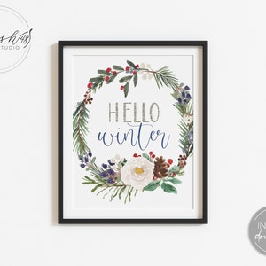 May include: A printable art print with a watercolor wreath of winter greenery, berries, and a white flower. The text "Hello Winter" is written in the center of the wreath in a silver glitter font.