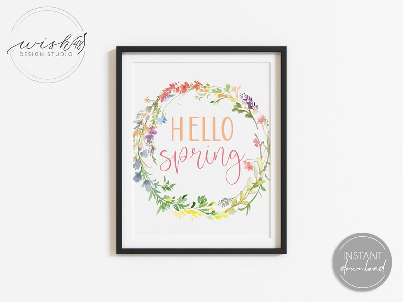 May include: A printable art print with a watercolor wreath of flowers in shades of pink, yellow, blue, and green. The wreath surrounds the text "Hello Spring" in pink and orange.