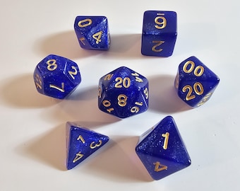 May include: A set of seven blue polyhedral dice with gold numbering. The dice are arranged in a circular pattern, with a variety of shapes including a d4, d6, d8, d10, d12, d20, and a percentile die. The dice are for tabletop games.