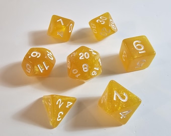 May include: A set of seven yellow resin dice with white numbering. The dice are in various shapes, including a d4, d6, d8, d10, d12, d20, and a d30. The dice have a glittery appearance.