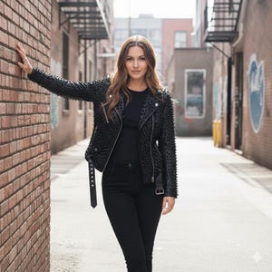 May include: A black leather motorcycle jacket featuring silver-toned hardware, a notched lapel, and an all-over studded design. The jacket includes a front zipper closure, a buckled belt at the hem, and long sleeves, worn over a plain black top and jeans.