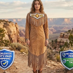 May include: A tan suede dress with long sleeves and fringe. The neckline has a geometric pattern. The dress is worn with brown boots. The backdrop is a desert landscape. The dress is approximately 150 cm in length.