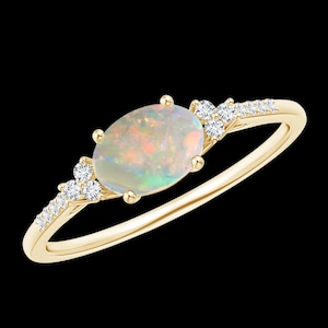 May include: A gold ring featuring an oval opal gemstone with iridescent colors. The ring is accented with small, round diamonds and has a delicate band. The opal is the focal point, showcasing a play of colors.