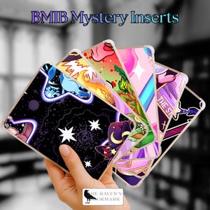 May include: A hand holding a fan of clear phone case inserts with colorful designs. The inserts feature illustrations of stars, a wizard hat, and other fantasy-themed graphics. Text at the top reads "BMIIB Mystery Inserts".