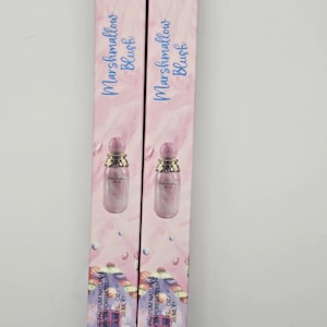 May include: Two pink boxes of "Marshmallow Blush" perfume. Each box features a small perfume bottle with a pink cap and a pink liquid. The boxes have a marble-like pattern and the text "EAU DE PARFUM NATURAL SPRAY VAPORISATEUR 1.18 FL OZ / 35 ML E".