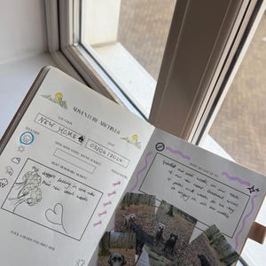 Op de afbeelding: Open dagboek met de titel "Adventure Archives", de locatie "New Home" en de datum "03/06/2024". Het dagboek bevat krabbels, foto's van honden en handgeschreven notities over hun avonturen.