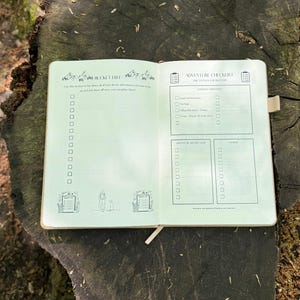 Op de afbeelding: Open journal met een bruine kaft, met een "Bucket List" en "Adventure Checklist" lay-out. De linkerpagina heeft een lijst met selectievakjes en bergillustraties. De rechterpagina heeft checklists voor inpakken en avontuurlijke doelen.