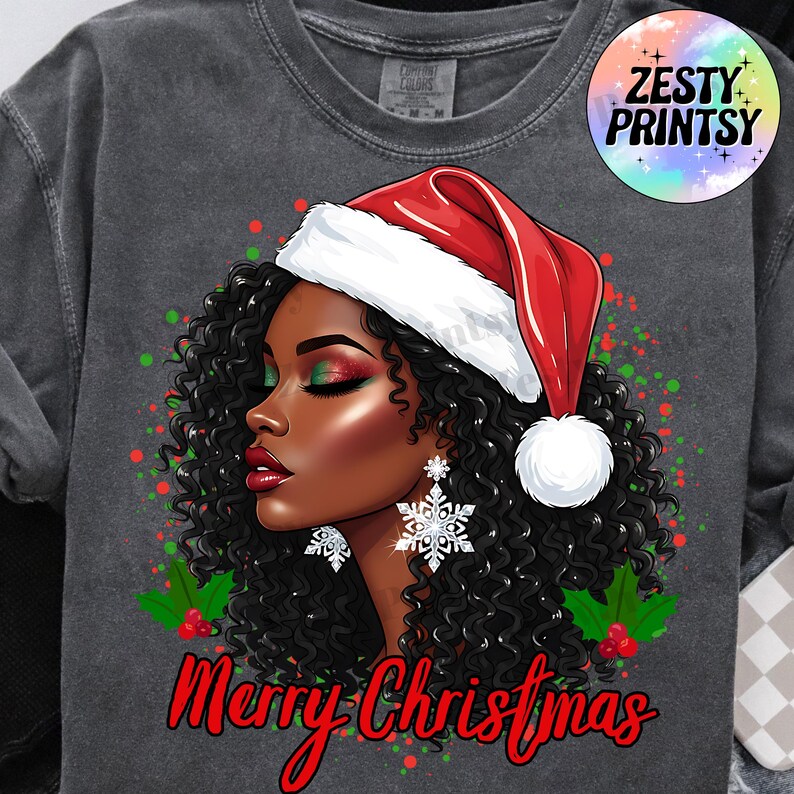 May include: Dark gray sweatshirt featuring a graphic of a woman with curly black hair wearing a Santa hat and snowflake earrings. The words "Merry Christmas" are written in red script below the image.