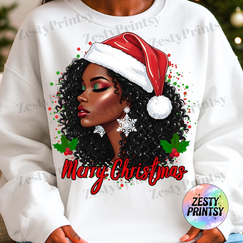 May include: White sweatshirt featuring a graphic of a Black woman wearing a Santa hat and snowflake earrings. The design includes the text "Merry Christmas" in red script, with green and red accents. The Zesty Prints logo is in the lower right corner.