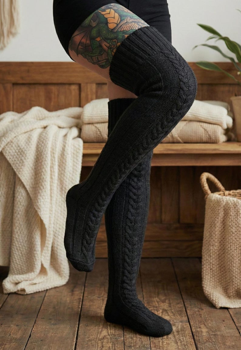May include: Dark gray, cable-knit over-the-knee socks. The socks have a ribbed texture on the leg and a cable-knit design on the upper thigh. The socks are made of a thick, warm material, perfect for cold weather.