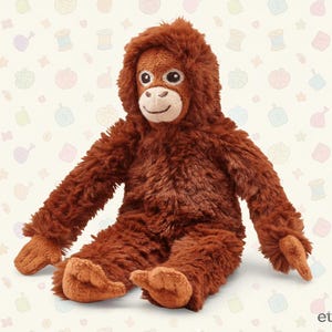 Puede incluir: Un peluche de orangután con pelaje marrón, una capucha y una cara sonriente. El animal de peluche está sentado con los brazos y las piernas extendidos. El juguete está hecho de un material suave y difuso y está diseñado para parecerse a un orangután real.
