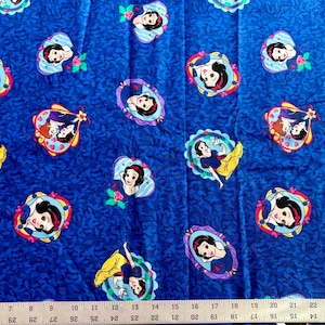 May include: Blue fabric with a repeating pattern of Snow White illustrations in various poses and frames. The fabric features a dark blue background with a subtle floral texture, and the Snow White images are in colorful frames.