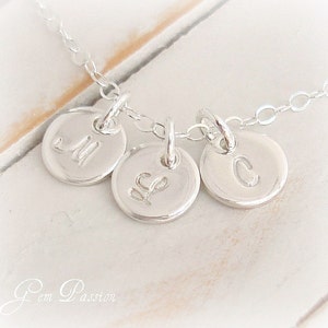 May include: Silver necklace with three round charms, each engraved with a letter: M, L, and C.