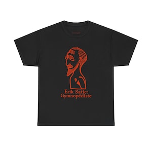 May include: Black t-shirt featuring an orange line drawing of a man's profile with a beard and glasses. The text "Erik Satie: Gymnopédiste" is printed below the illustration. The shirt is made of a soft material.