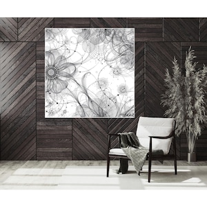 Op de afbeelding: Zwart-wit abstracte bloemenkunstprint. Het kunstwerk toont ingewikkelde lijntekeningen van bloemen en onderling verbonden vormen tegen een witte achtergrond. De print wordt weergegeven op een donkerhouten wand.