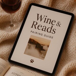 Peut inclure: Une tablette numérique affiche "Wine & Reads Pairing Guide" avec une image de cascade et une empreinte de patte. Un verre de vin rouge et un livre ouvert intitulé "Autumn Skies" sont également présents, sur une couverture en tricot crème.
