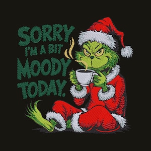 Op de afbeelding: Een geborduurd ontwerp op een zwarte achtergrond met een groen wezen in een rood kerstmanpak met witte bontrand, die een dampende witte koffiemok vasthoudt, met de groene tekst SORRY I'M A BIT MOODY TODAY links van de figuur.
