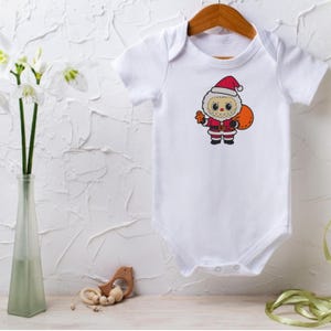 White baby onesie displayed on a hanger with a Santa monster embroidery design – Christmas digital embroidery file mockup for newborn and toddler clothing projects