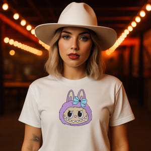 Woman in white hat wearing white t-shirt with purple kawaii monster bunny embroidery – cute cartoon digital machine embroidery mockup