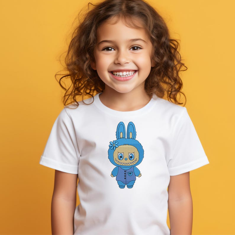 Smiling child wearing a white t-shirt with a blue bunny monster embroidery design – kid-friendly digital embroidery mockup for clothing projects