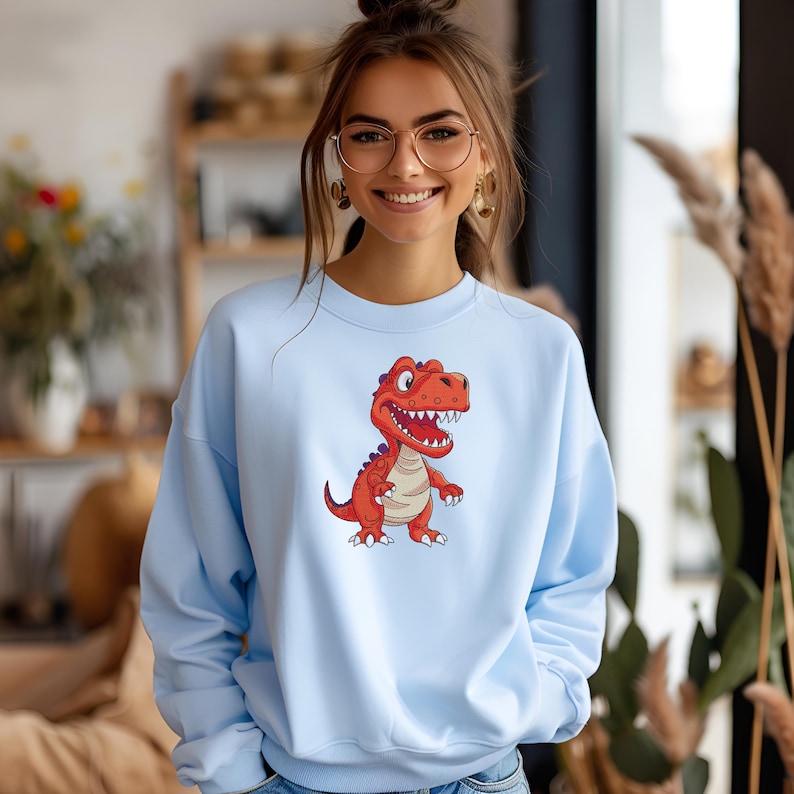 Woman wearing blue sweatshirt with cartoon dinosaur embroidery design T rex machine embroidery file for kids clothing projects