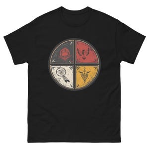 May include: Black t-shirt with a circular design divided into four sections. Each section features a Native American-inspired graphic in red, yellow, white, and black. The design includes a bear paw, eagle, dreamcatcher, and geometric shapes.