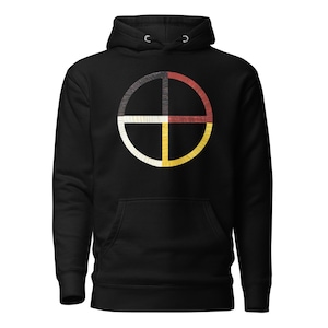Peut inclure: Sweat à capuche noir avec un motif circulaire divisé en quatre sections : noir, rouge, blanc et jaune. Le motif est centré sur la poitrine, avec une poche kangourou et une capuche à cordon.